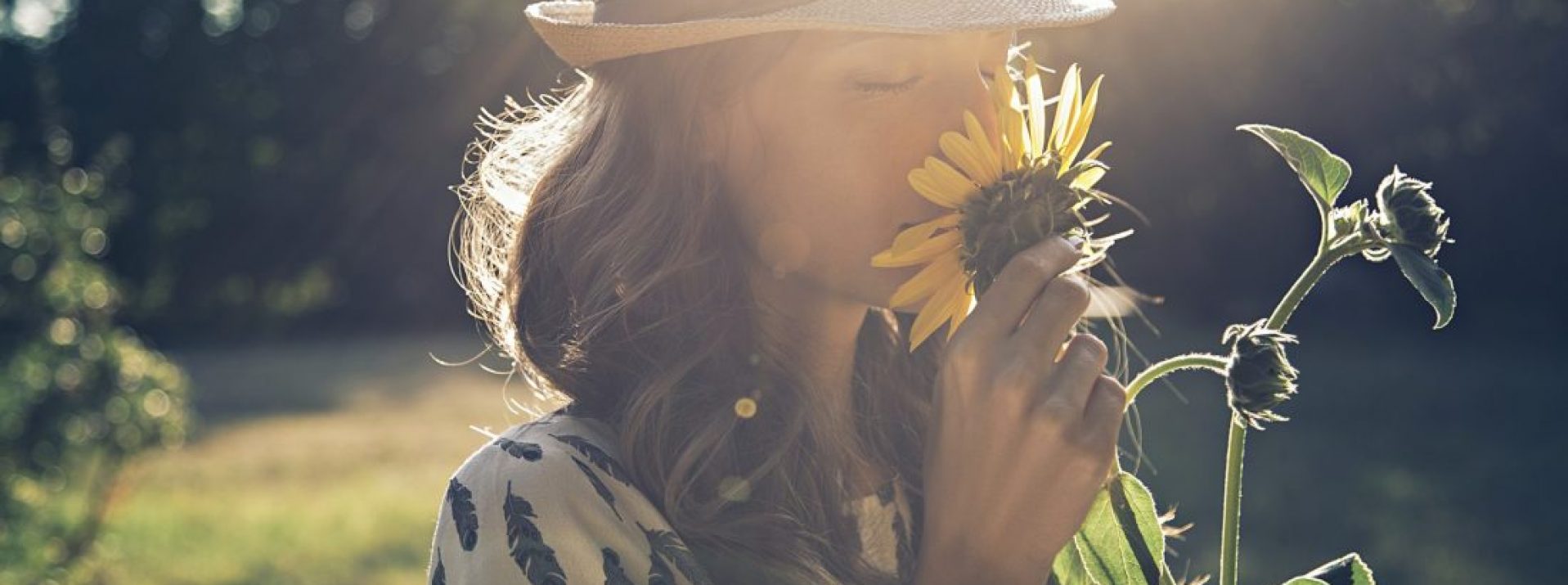 Girl smells sunflower in nature